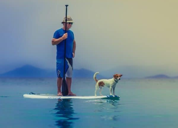 man and dog on paddleboard practicing humility