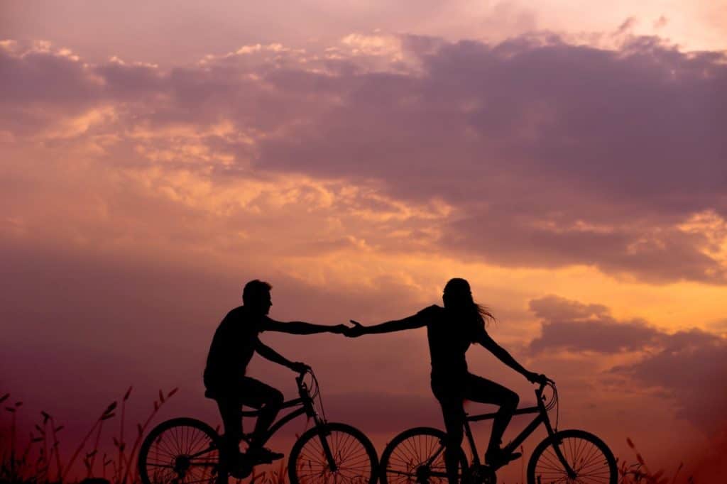 Couple on bicycles at sunset offering validation