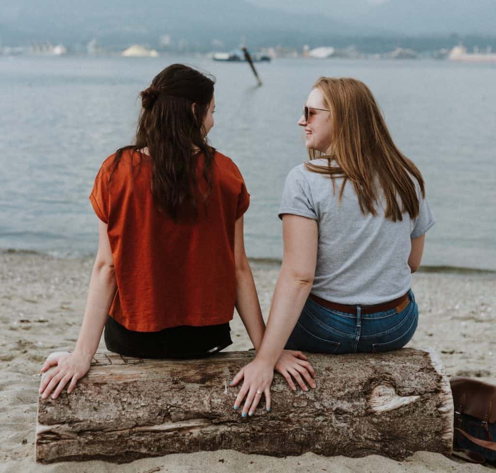 2 friends on beach offering each other affirmation