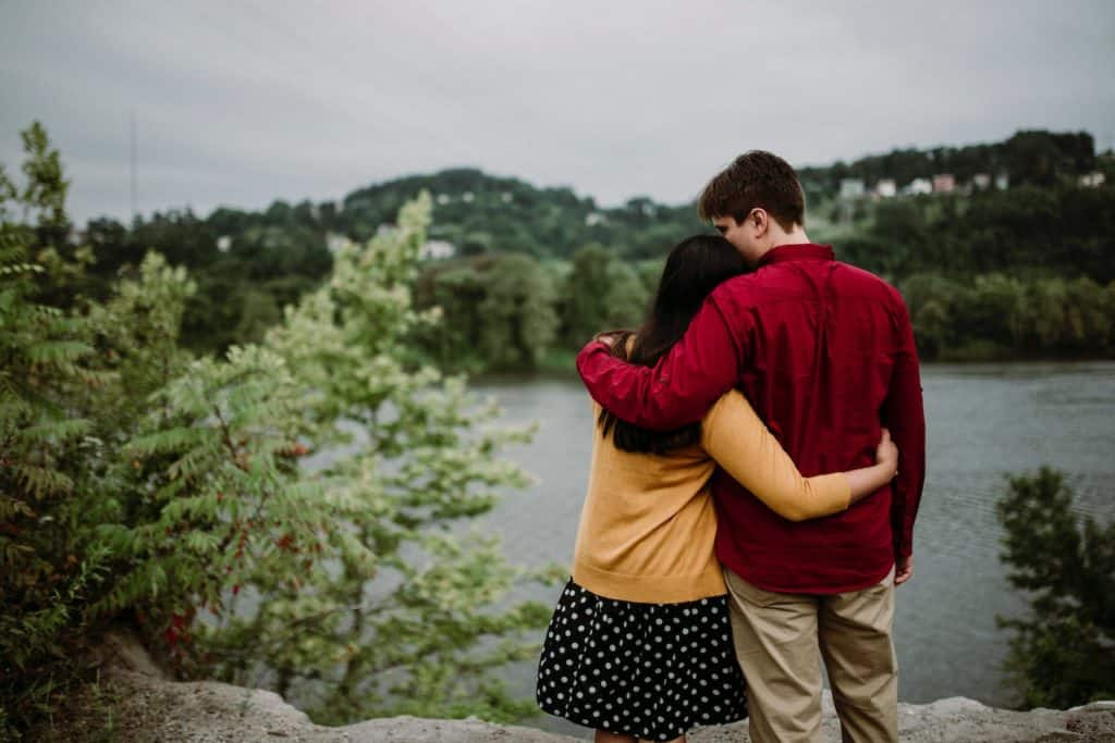 couple offering each other comfort by lake with trees