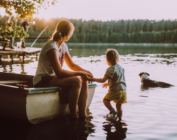 Mother reflects on financial freedom (with child and dog by water)