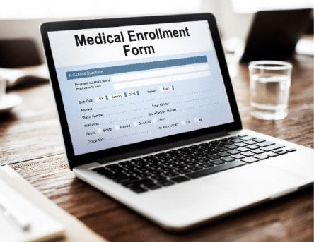 Laptop on desk with "Medical Enrollment Form" written on the screen.