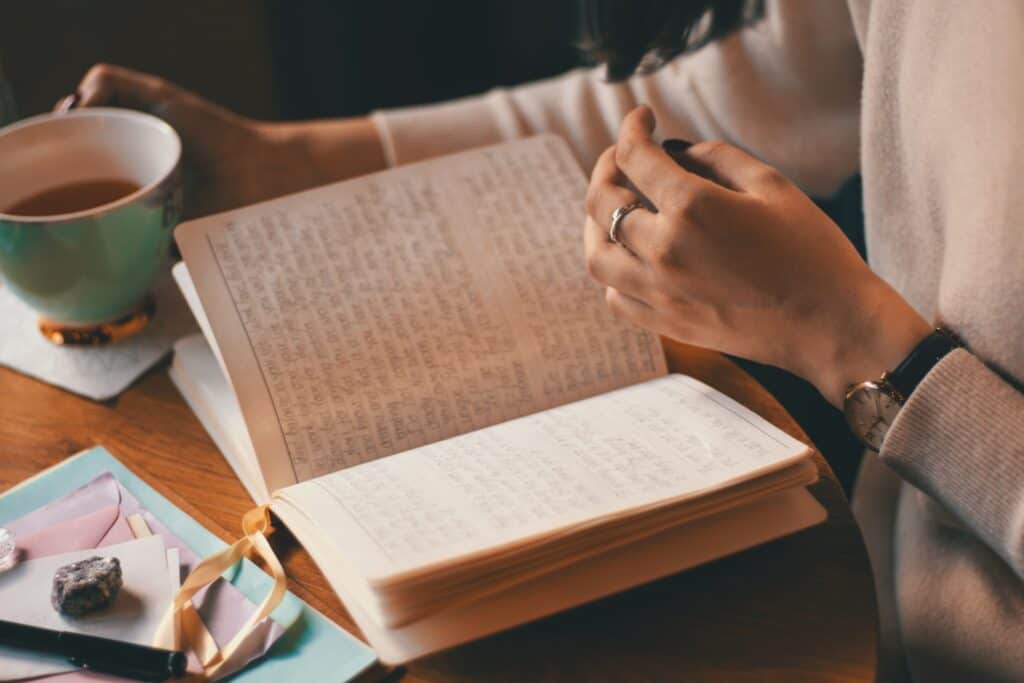 Woman reading journal and drinking coffee.