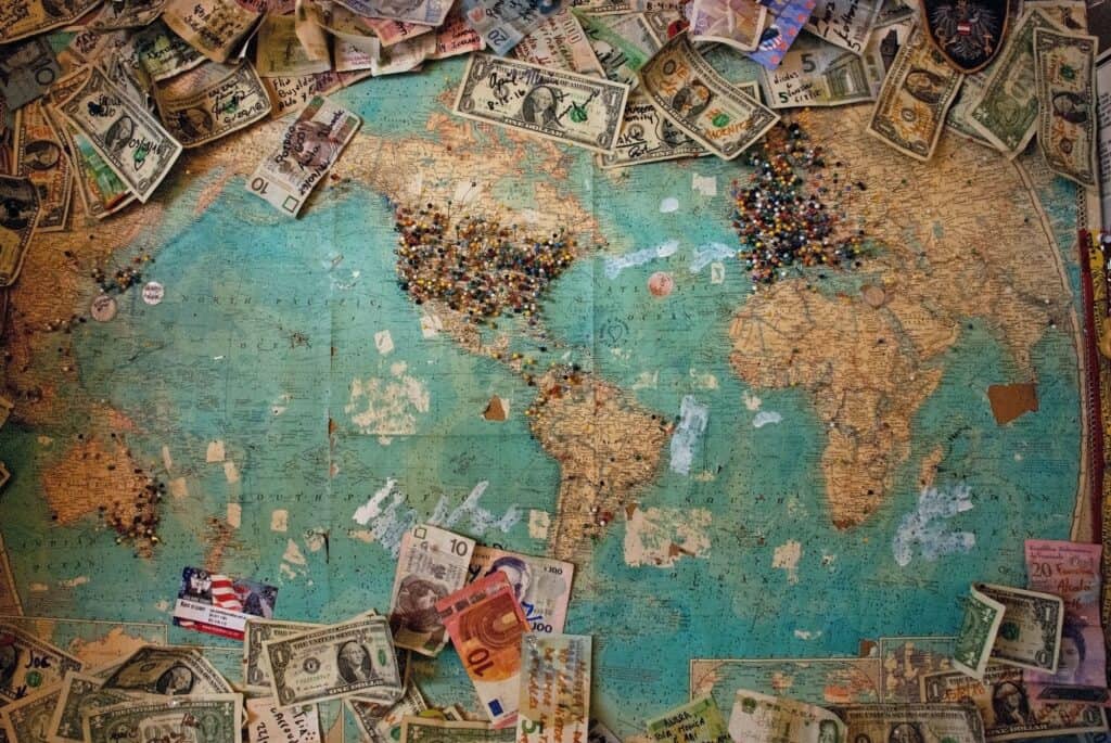 International map marked with pins on specific locations and surrounded by global currency.
