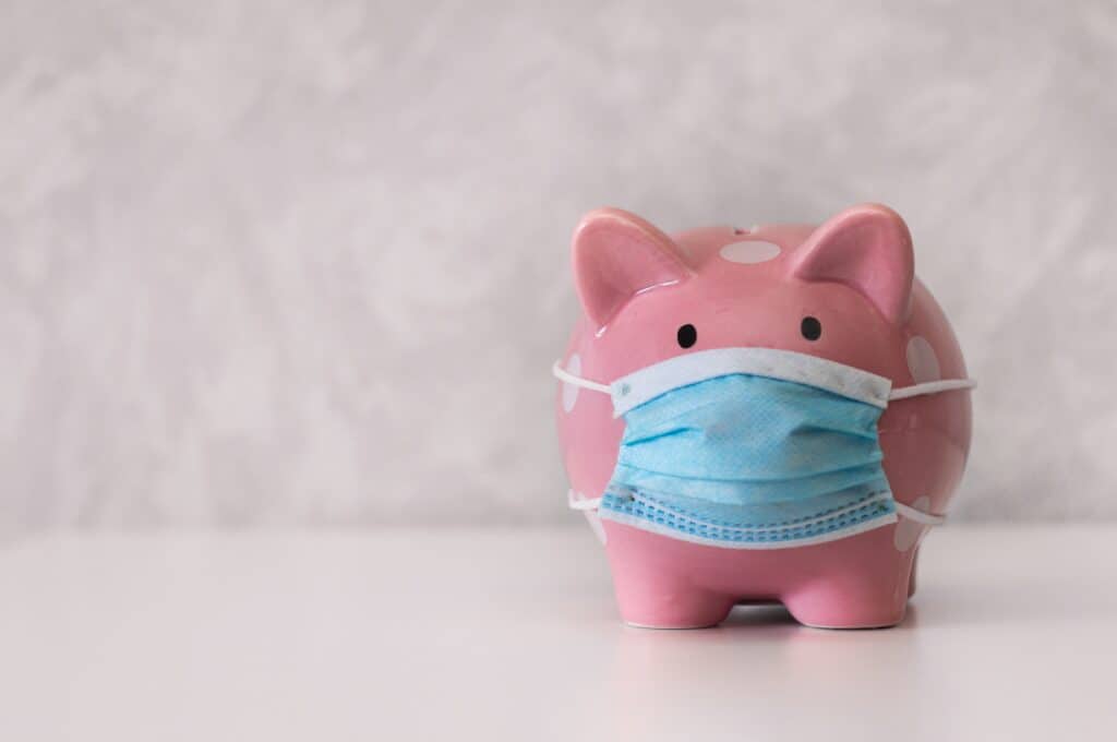 Pink piggy bank against a white background wearing a mask.