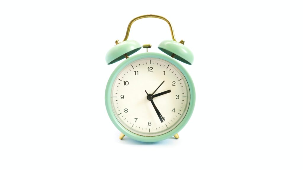mint green alarm clock sitting on a white background.