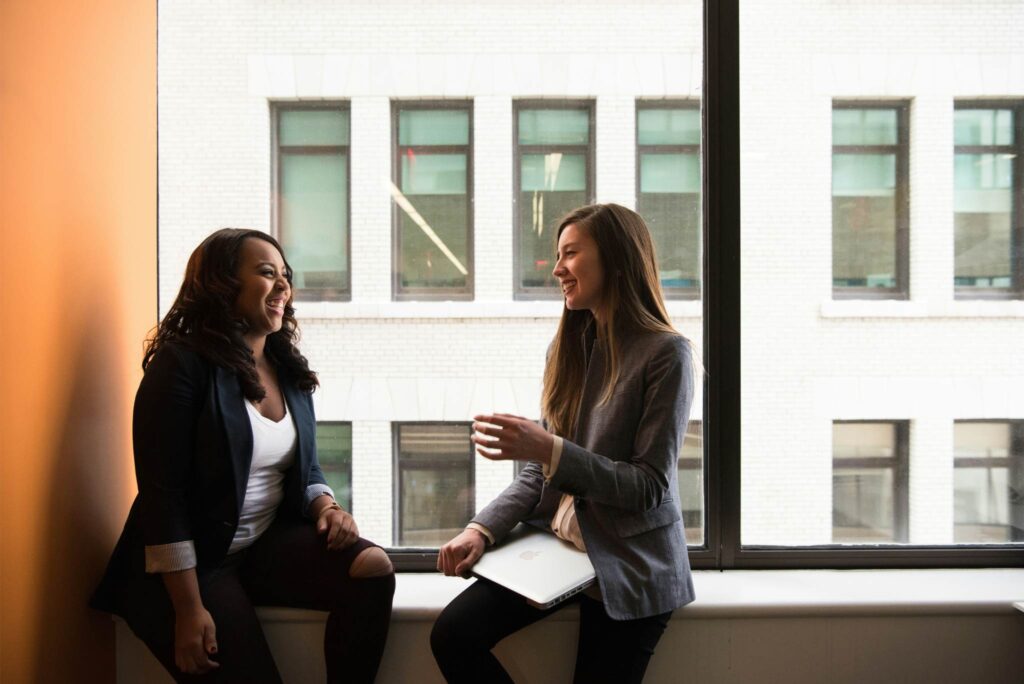 Two woman sitting by a window talking